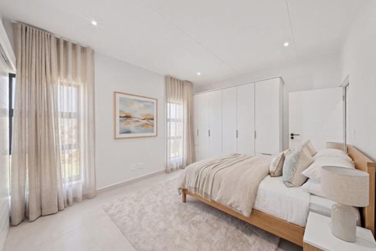 A bright and modern bedroom featuring neutral tones, tiled flooring, recessed downlights, and ample built-in cupboard storage.