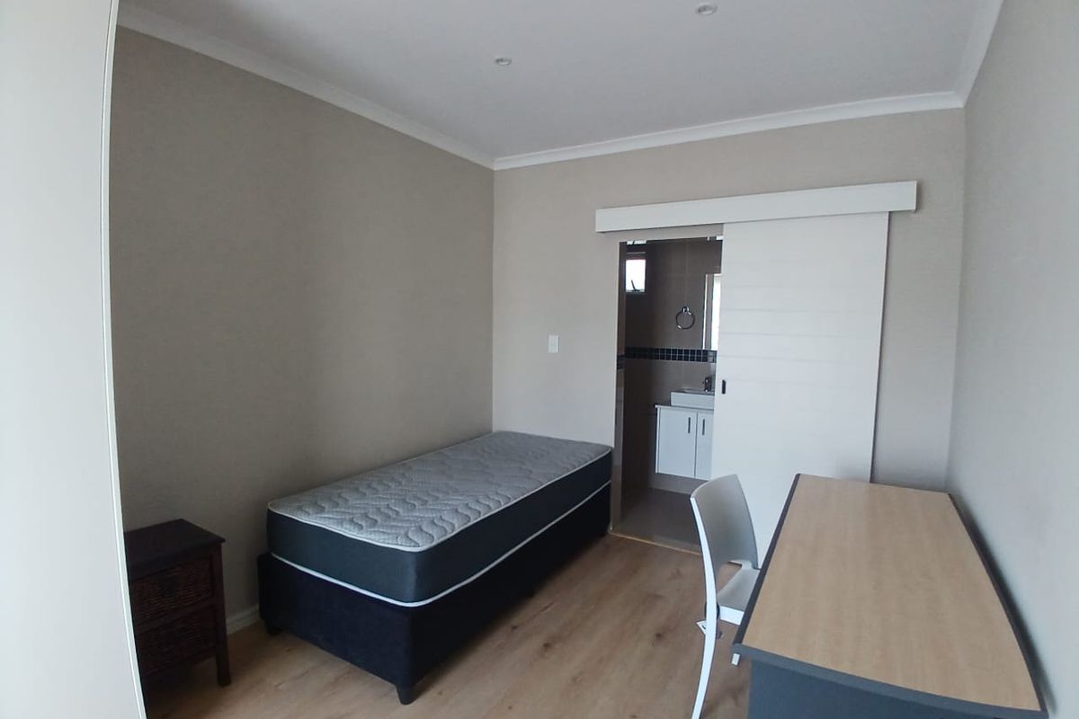 A well-maintained bedroom featuring laminate flooring, recessed lighting, and a convenient sliding door leading to an en-suite bathroom.