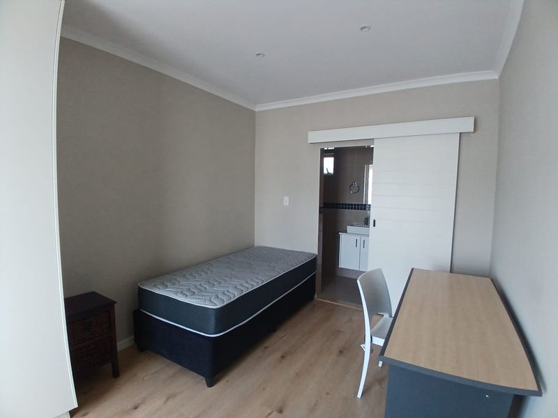 A well-maintained bedroom featuring laminate flooring, recessed lighting, and a convenient sliding door leading to an en-suite bathroom.