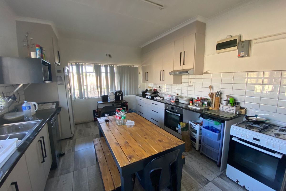 A functional kitchen featuring light-toned cabinetry, tiled splashbacks, a built-in oven, and a freestanding stove, providing a practical workspace for daily meal preparation.
