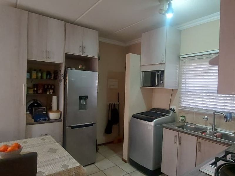 Open plan kitchen and dining area featuring built-in cabinetry, gas hob, stainless steel sink, and tiled flooring.