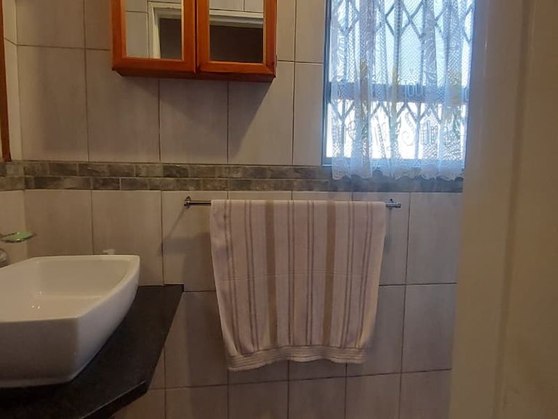A functional bathroom featuring a modern vessel sink on a stone vanity, tiled walls, and a wall-mounted medicine cabinet.