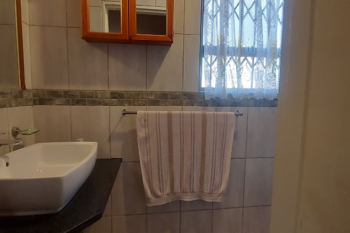 A functional bathroom featuring a modern vessel sink on a stone vanity, tiled walls, and a wall-mounted medicine cabinet.