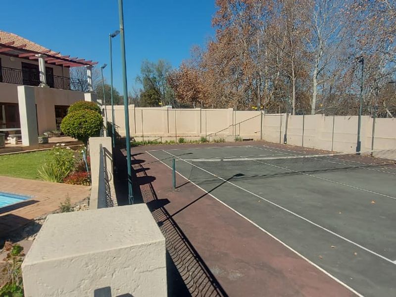 Outdoor recreational area featuring a private tennis court, swimming pool, and a covered patio with a pergola attached to the main residence.