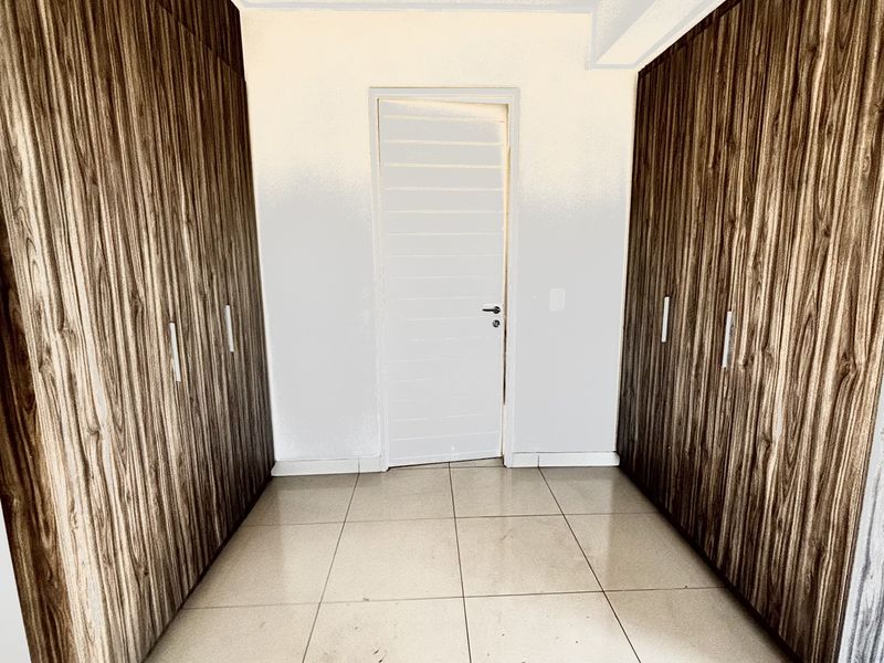 A hallway or dressing area featuring extensive floor-to-ceiling built-in wooden cabinetry and large format floor tiles.