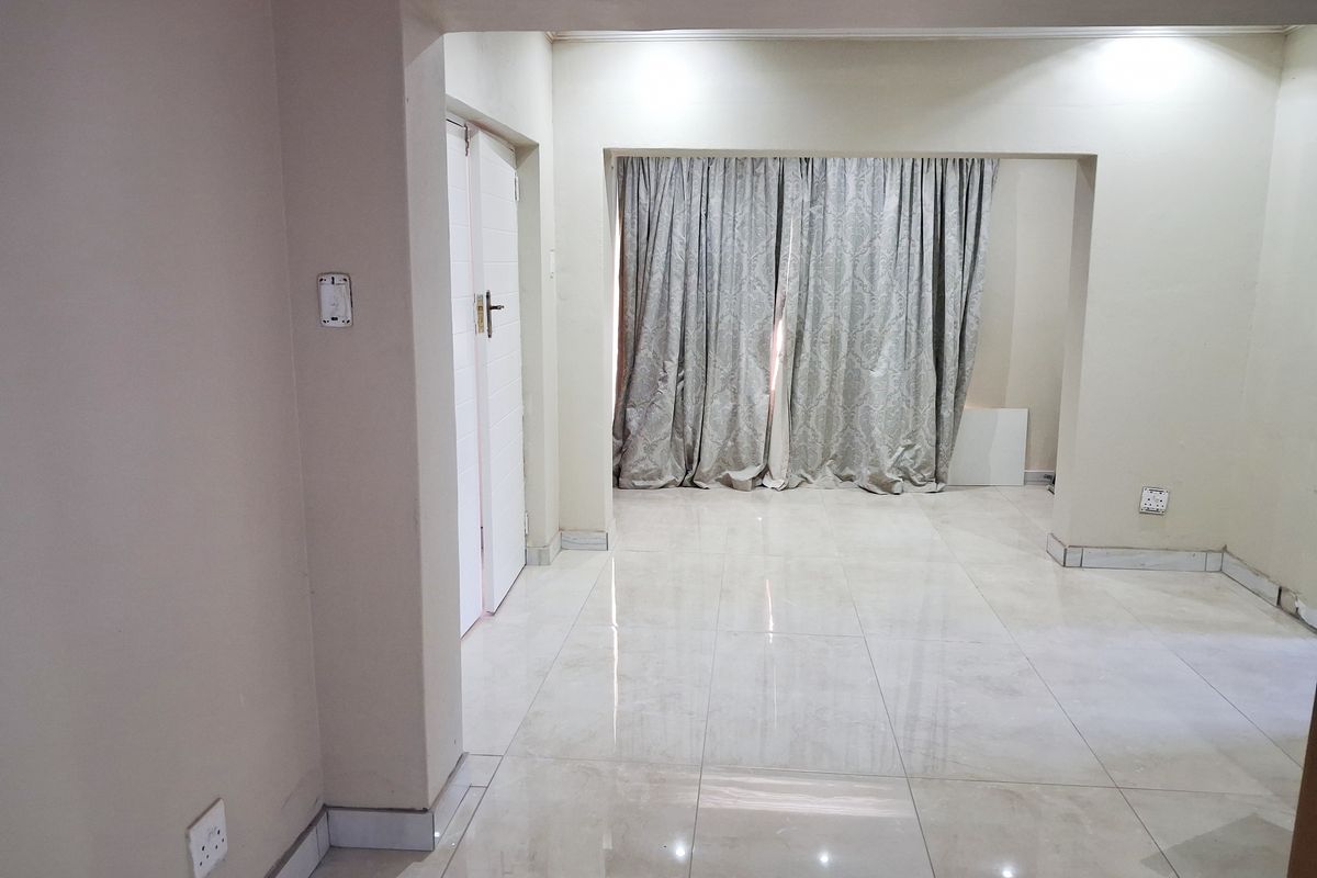 An empty living area featuring neutral tiled flooring and clean walls, providing a blank canvas for interior design and furniture placement.
