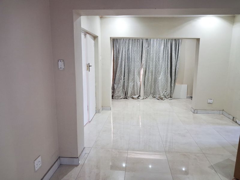 An empty living area featuring neutral tiled flooring and clean walls, providing a blank canvas for interior design and furniture placement.