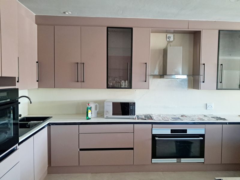 A modern kitchen featuring mauve cabinetry, built-in oven, extractor fan, and a clean countertop, providing a functional workspace with contemporary design elements.