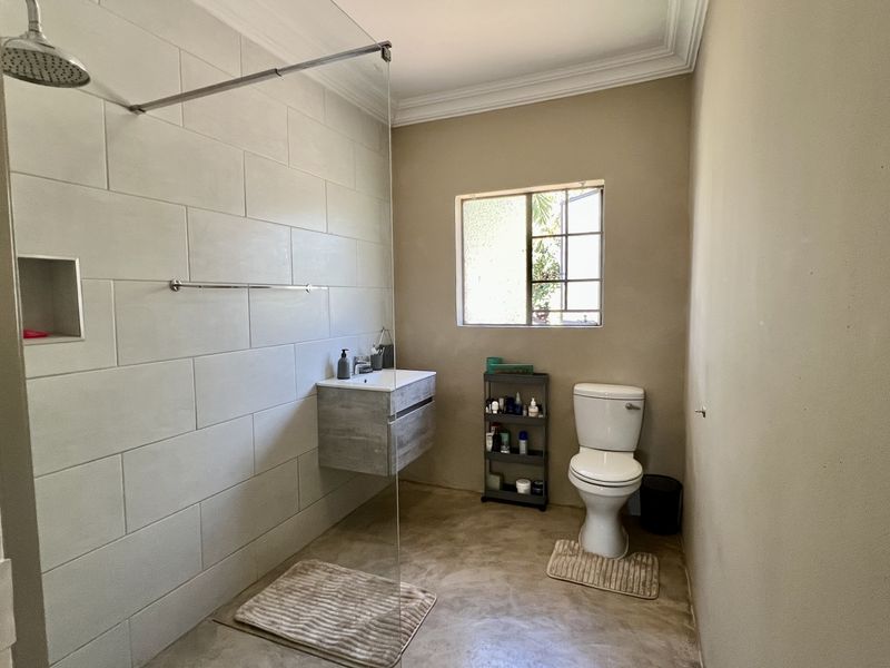 Modern bathroom featuring a walk-in shower with a rain shower head, a wall-mounted vanity, and a toilet, finished with neutral wall tones.