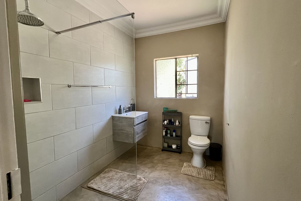 Modern bathroom featuring a walk-in shower with a rain shower head, a wall-mounted vanity, and a toilet, finished with neutral wall tones.