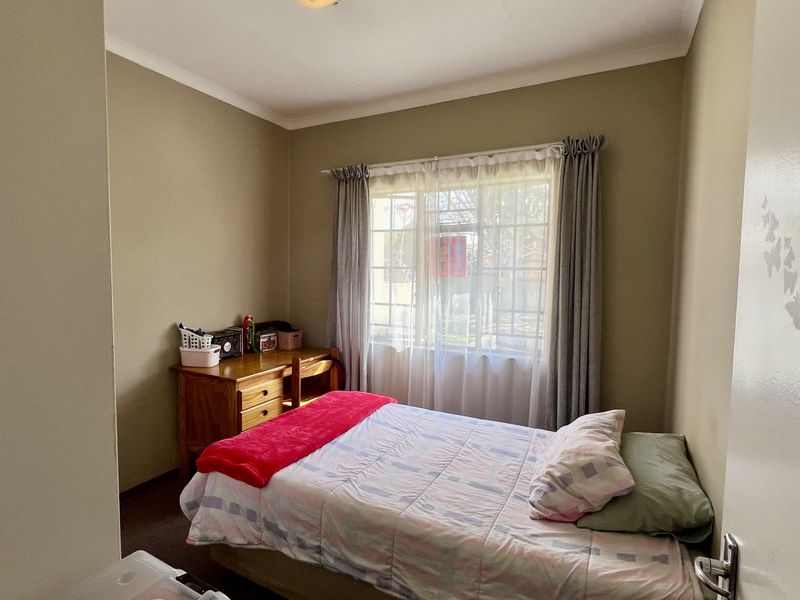 A standard bedroom featuring neutral wall tones and a window with fitted curtain rails, providing natural light and a functional living space.