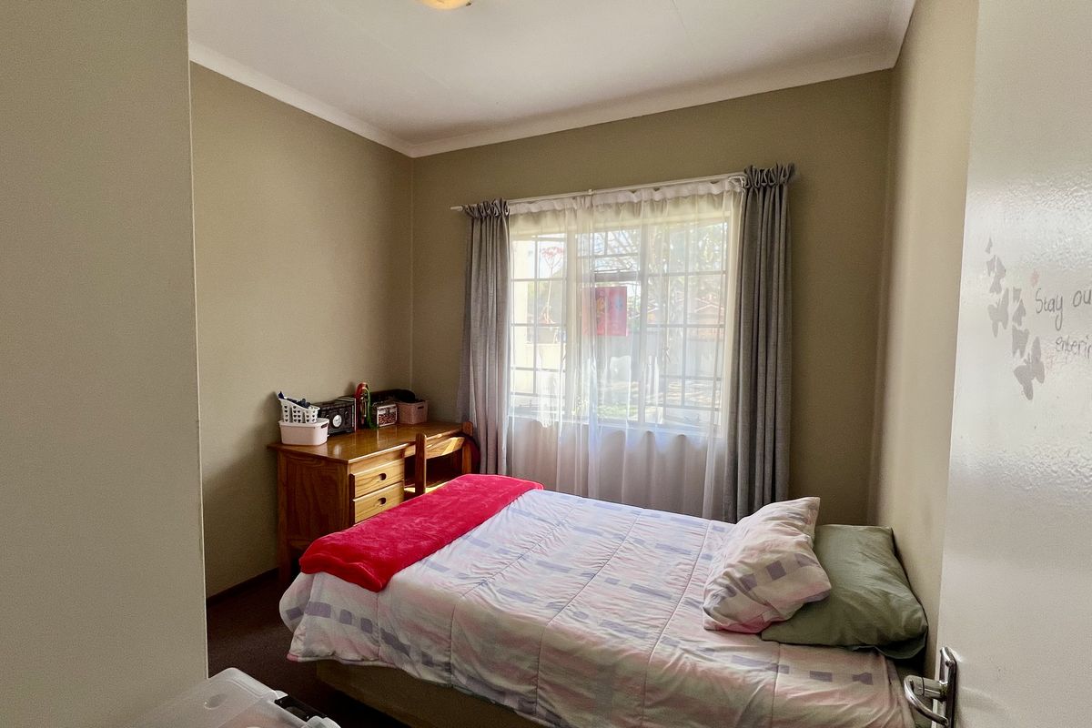A standard bedroom featuring neutral wall tones and a window with fitted curtain rails, providing natural light and a functional living space.