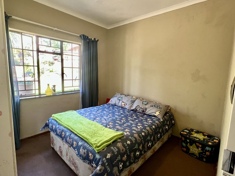 A bedroom featuring a steel-framed window and carpeted flooring, requiring cosmetic updates to the wall finishes and flooring to improve its overall condition.