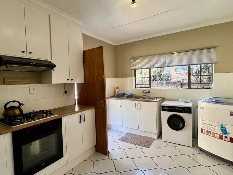 Functional kitchen featuring white cabinetry, gas hob, electric oven, extractor fan, and tiled flooring with integrated laundry appliance space.