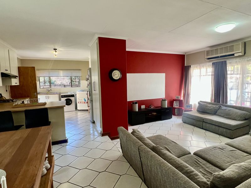 Open-plan living and kitchen area featuring tiled flooring, built-in cabinetry, and an integrated air conditioning unit, creating a functional and connected living space.