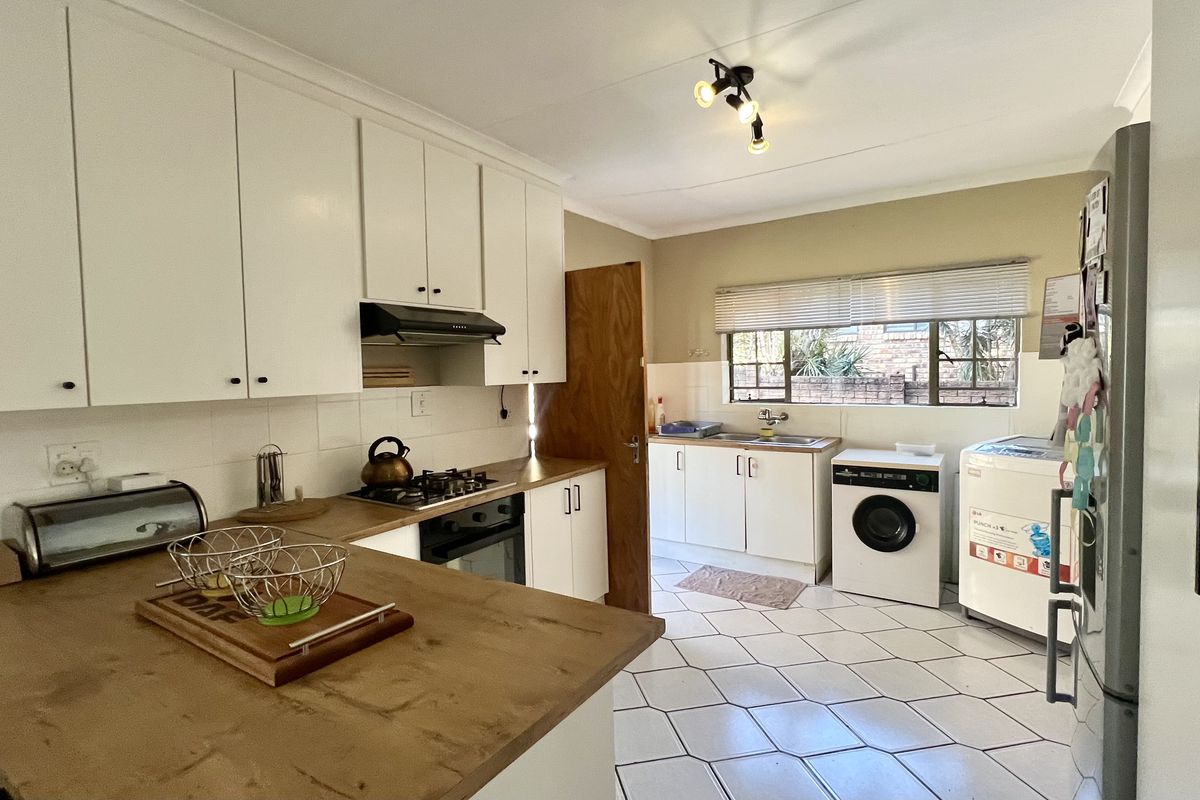 Functional kitchen featuring white cabinetry, gas hob, under-counter oven, and tiled flooring with integrated laundry area.