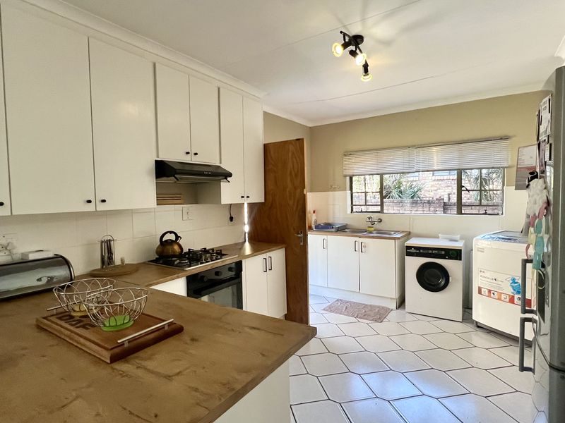 Functional kitchen featuring white cabinetry, gas hob, under-counter oven, and tiled flooring with integrated laundry area.