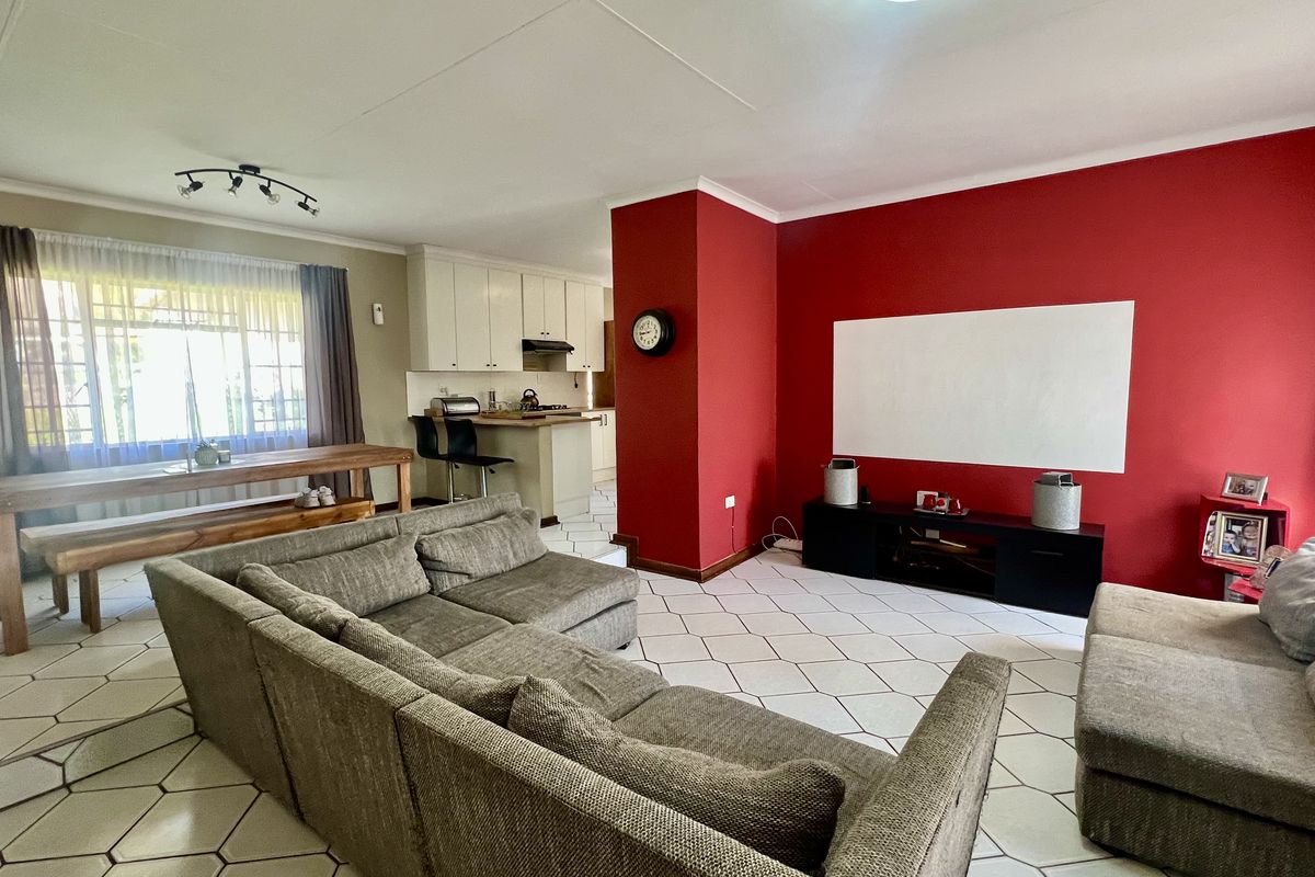 Open-plan living and kitchen area featuring tiled flooring, a breakfast bar, and a central red feature wall.