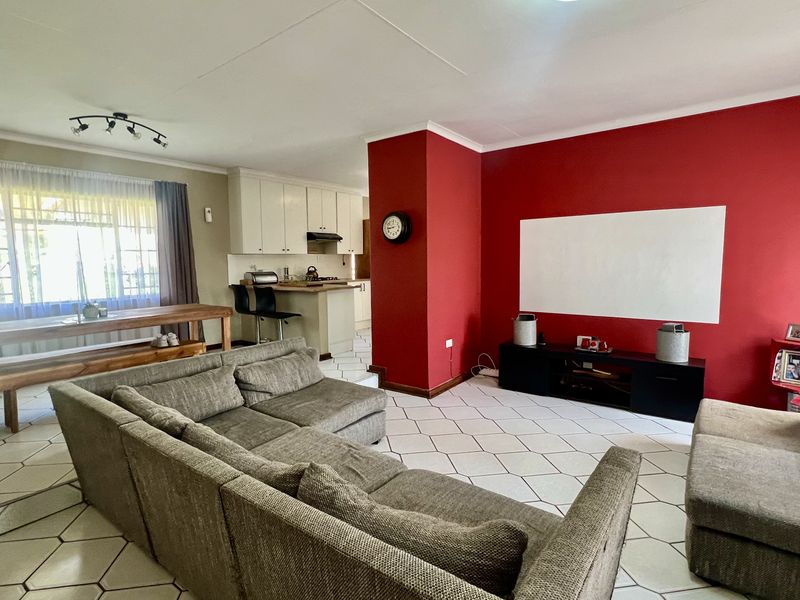 Open-plan living and kitchen area featuring tiled flooring, a breakfast bar, and a central red feature wall.