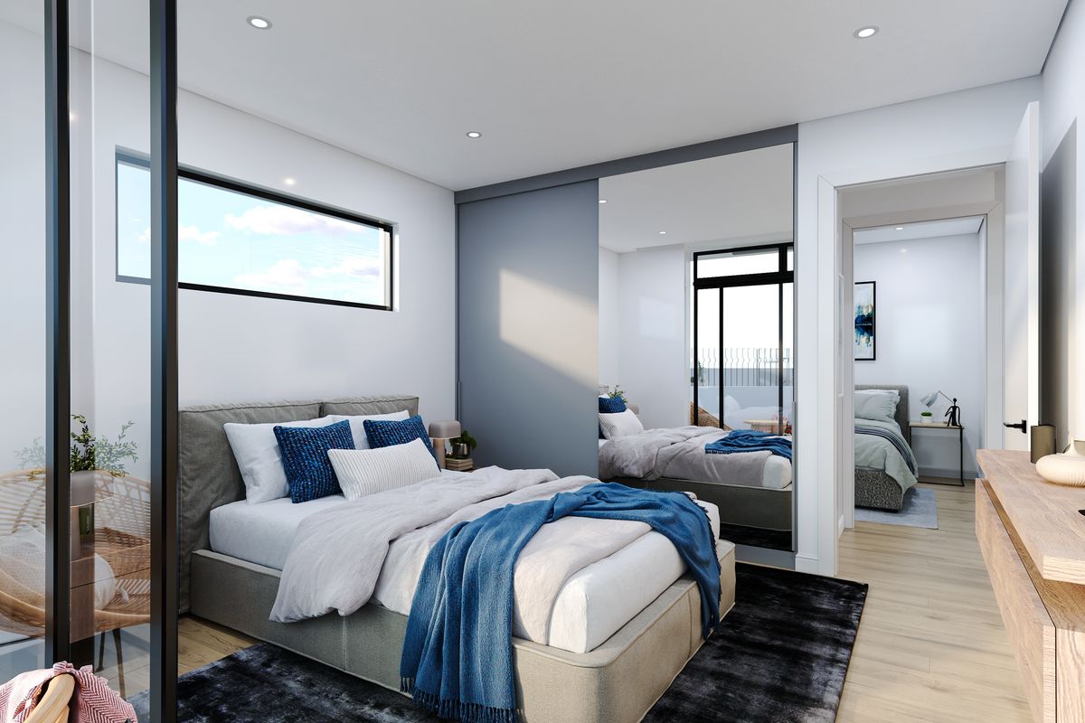 Modern bedroom featuring built-in mirrored wardrobes, recessed ceiling lighting, and large windows, offering a bright and contemporary living space.