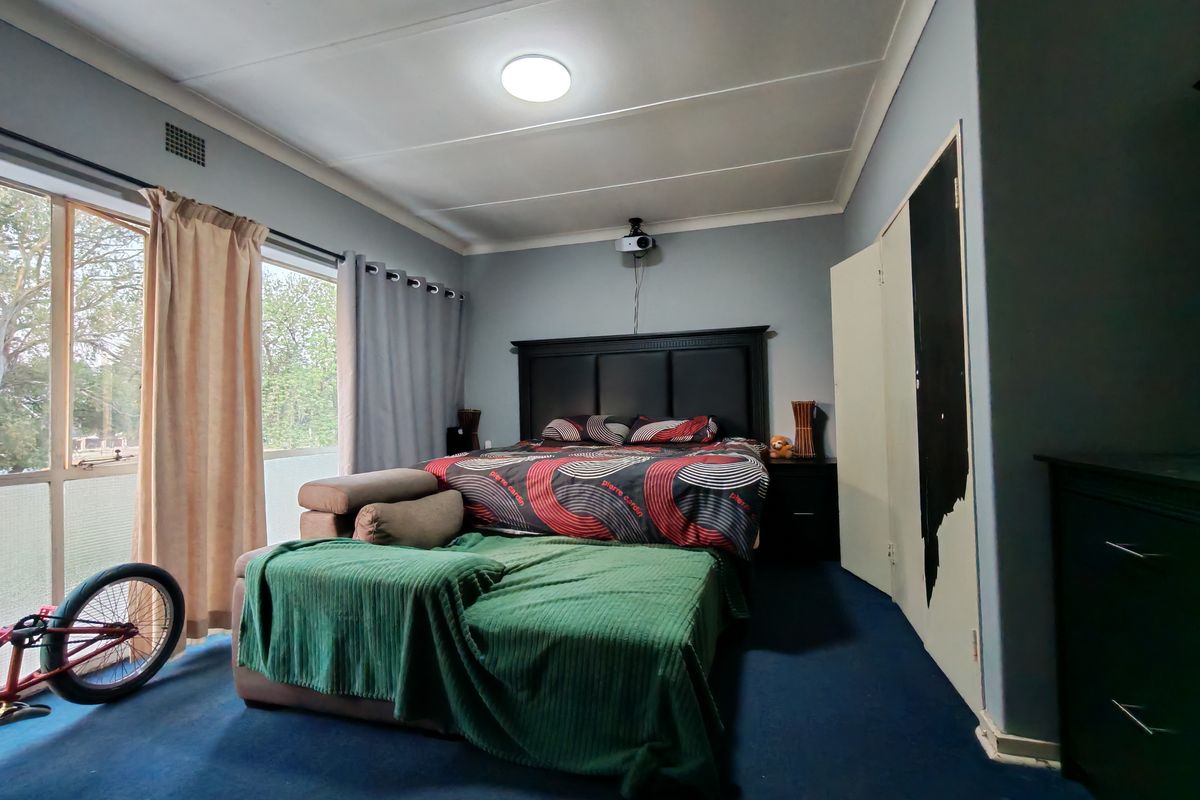 A bedroom featuring built-in wardrobes, large windows with natural light, and a ceiling-mounted projector.