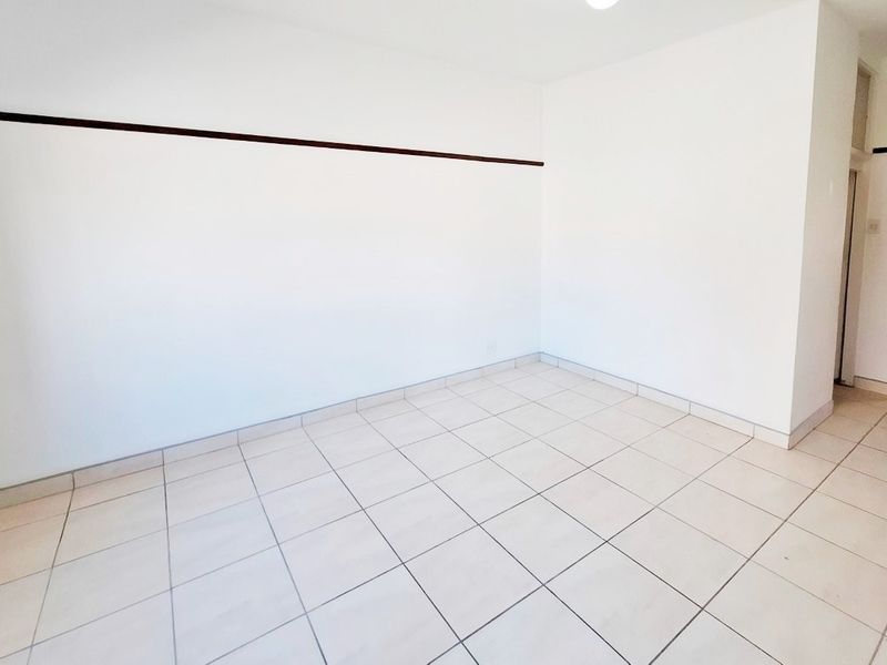 A bright, empty living area featuring neutral tiled flooring and clean white walls, providing a versatile blank canvas for interior design.