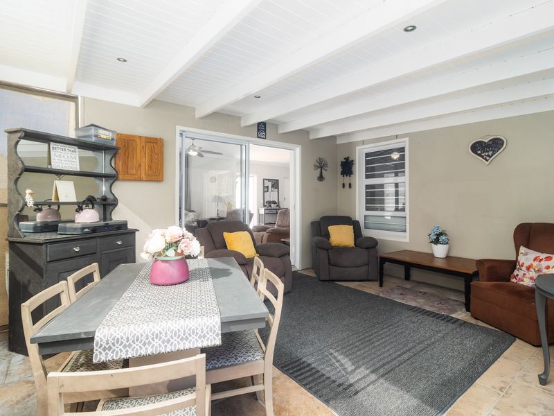 A covered patio area featuring tiled flooring, exposed beam ceilings with recessed lighting, and sliding glass doors providing access to the interior living space.