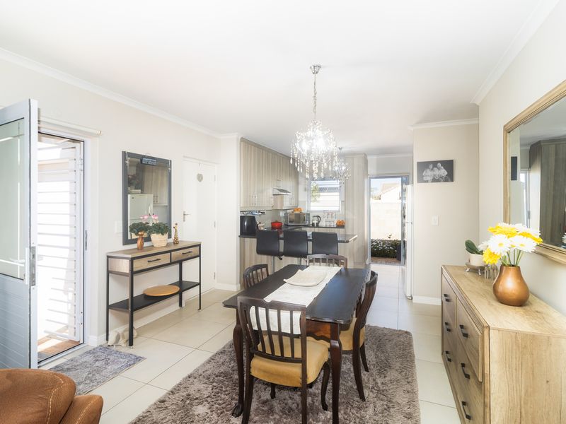 Open-plan dining and kitchen area featuring modern cabinetry, tiled flooring, and a breakfast bar, creating a functional and connected living space.
