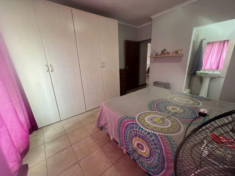 Bedroom featuring built-in cupboards, tiled flooring, and an en-suite area with a pedestal basin.