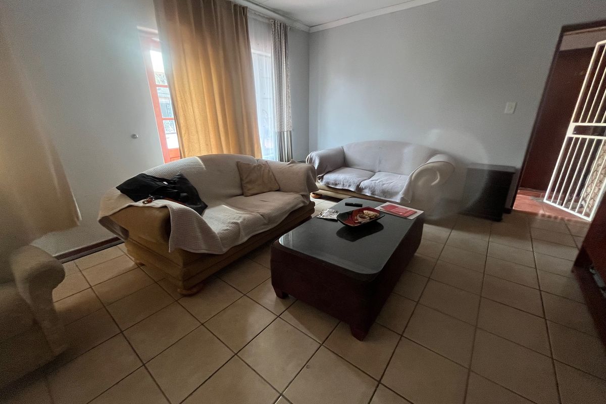 A living room featuring ceramic floor tiles, a sliding door with access to the exterior, and a security gate.