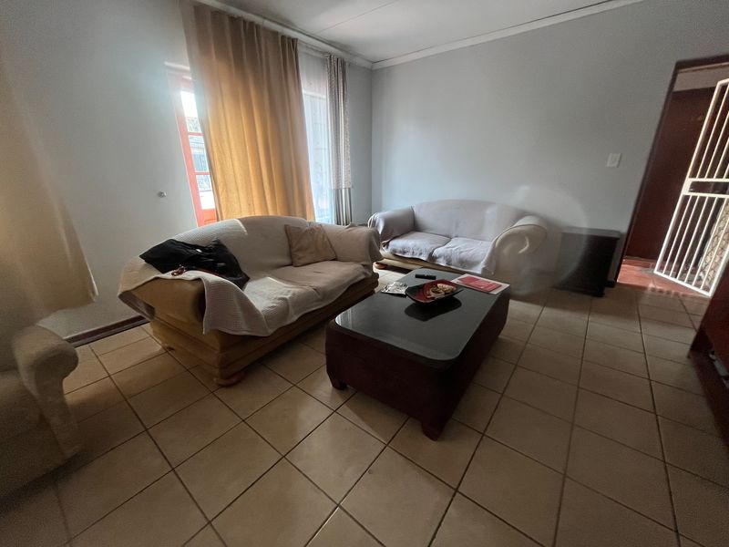 A living room featuring ceramic floor tiles, a sliding door with access to the exterior, and a security gate.