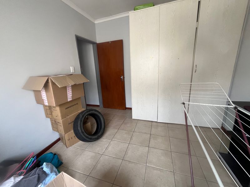 A bedroom featuring tiled flooring and a built-in wardrobe, providing a functional and neutral space ready for personalization.