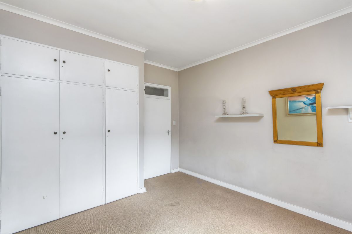 A bedroom featuring built-in cabinetry, neutral wall tones, and carpeted flooring, offering a functional and versatile living space.