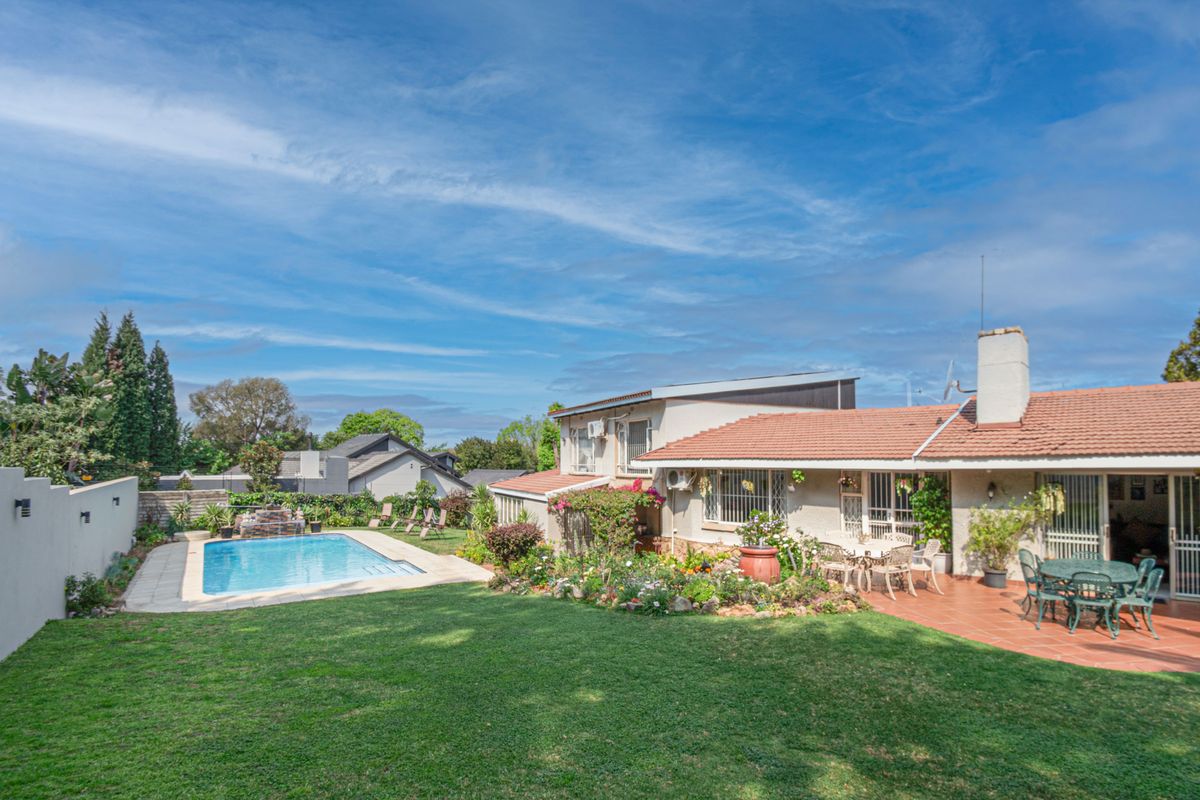 Spacious rear garden featuring a swimming pool, paved patio area, and established landscaping, providing an ideal space for outdoor relaxation and entertainment.