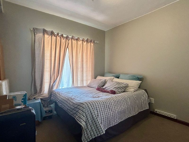 A functional bedroom featuring carpeted flooring and a window with installed curtain rods, providing a neutral space ready for personalization.