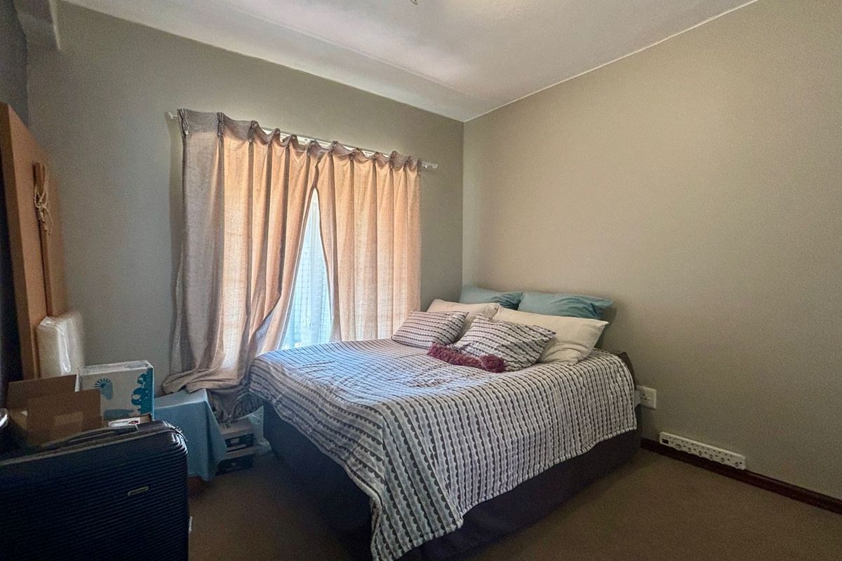 A functional bedroom featuring carpeted flooring and a window with installed curtain rods, providing a neutral space ready for personalization.