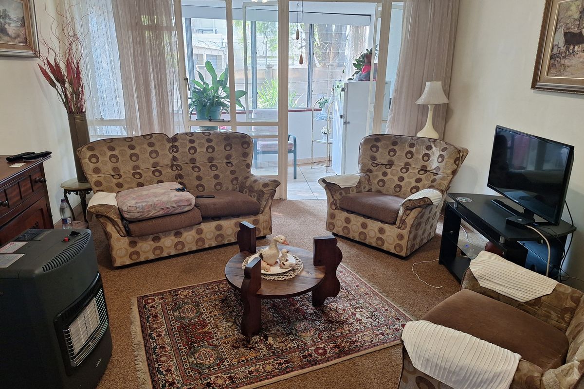 A carpeted living room featuring a large sliding glass door that provides access to an attached patio area.