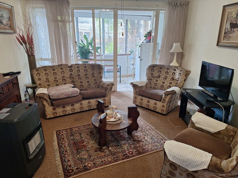 A carpeted living room featuring a large sliding glass door that provides access to an attached patio area.