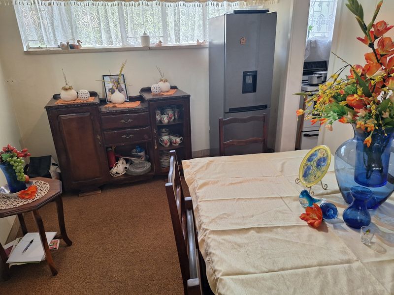 A dining area featuring carpeted flooring and a window with a sill, providing a functional space for meals.
