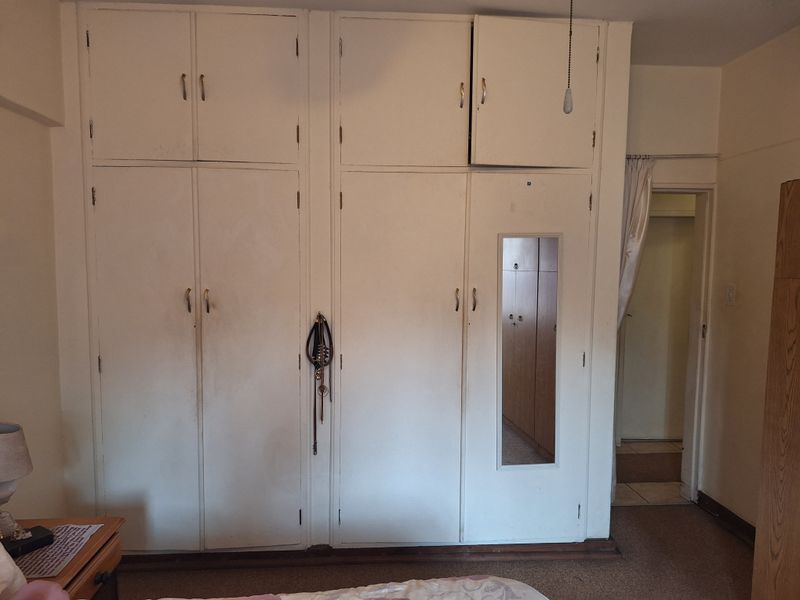 Bedroom featuring floor-to-ceiling built-in cupboards with an integrated mirror and overhead storage compartments.