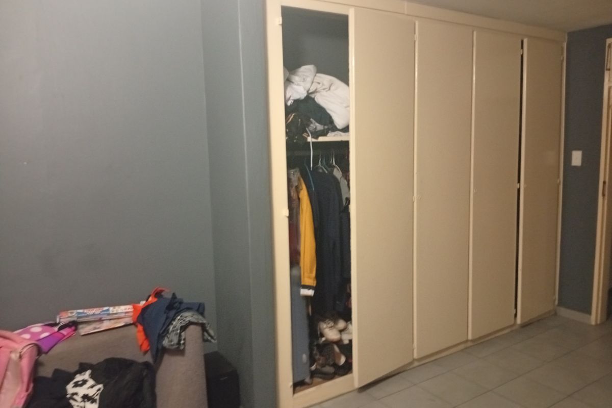 A bedroom featuring a large built-in wardrobe with multiple doors and tiled flooring.