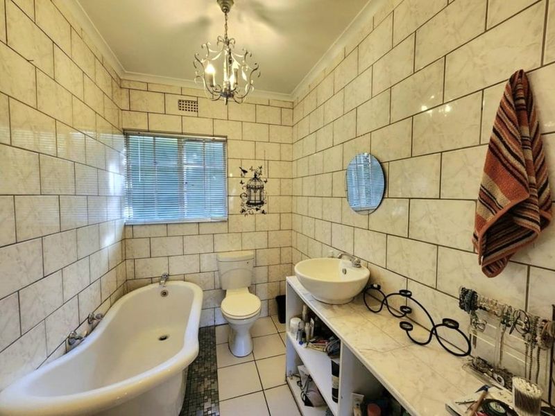 A bathroom featuring a freestanding bathtub, vessel sink on a vanity, and full-height ceramic wall tiling.