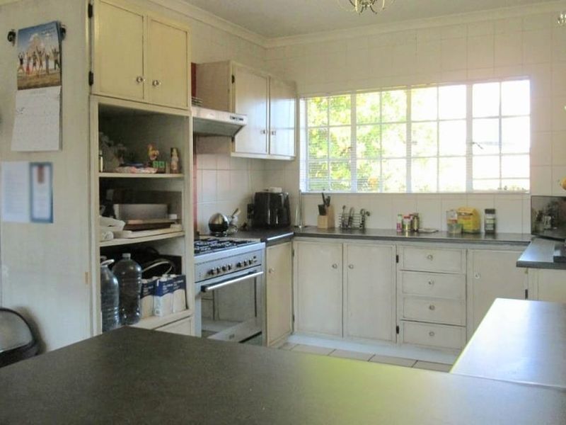 A functional kitchen featuring built-in cabinetry, laminate countertops, a gas stove with extractor fan, and tiled splashbacks, offering potential for modern updates.
