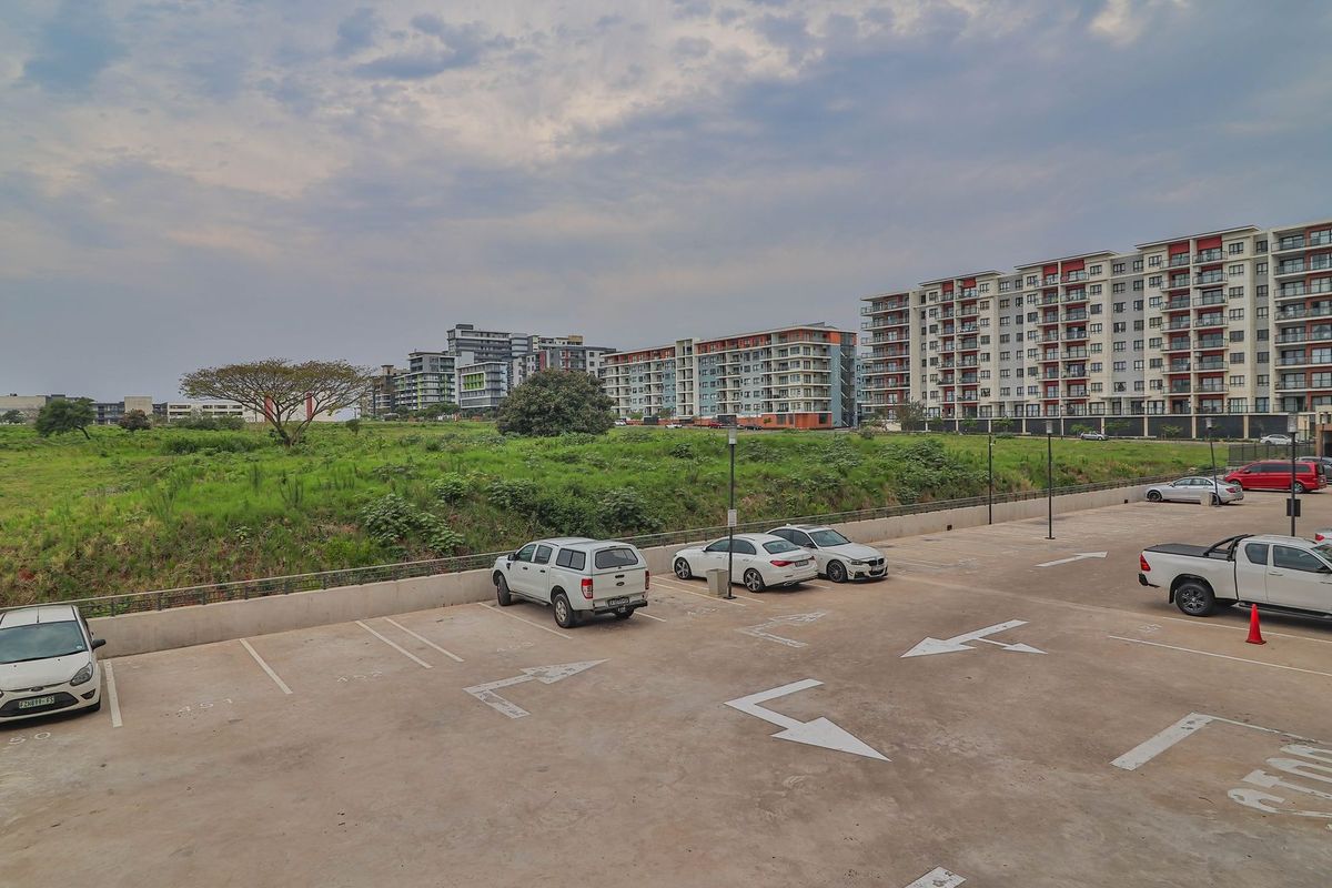 An elevated view of an apartment complex parking area with paved bays and surrounding landscaped grounds.