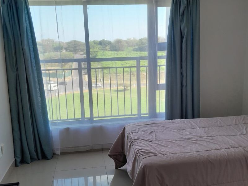 A bright bedroom featuring large sliding windows with natural light, tiled flooring, and a pleasant exterior view.