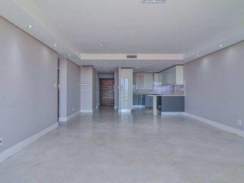 Spacious open-plan living area featuring polished concrete floors, recessed lighting, and a modern kitchen with integrated cabinetry.