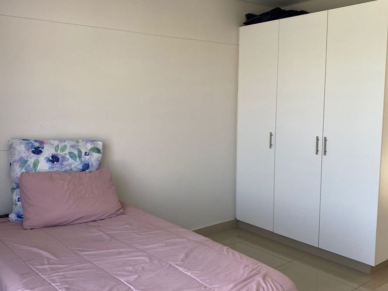A clean bedroom featuring neutral tiled flooring, a white built-in wardrobe, and a simple flush mount ceiling light.