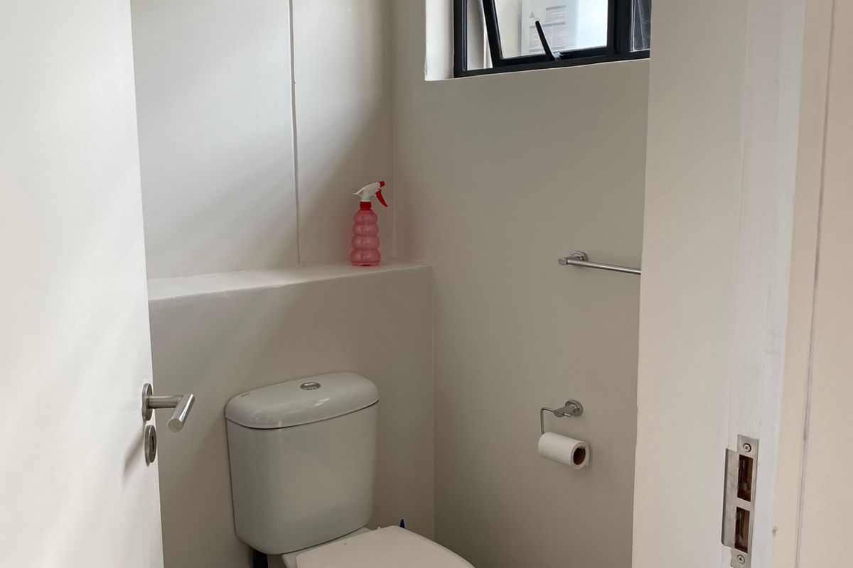 A compact, clean guest bathroom featuring a modern toilet, towel rail, and a top-hung window for ventilation.