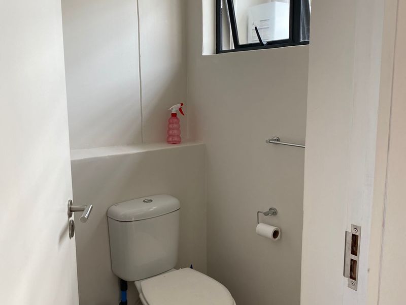 A compact, clean guest bathroom featuring a modern toilet, towel rail, and a top-hung window for ventilation.
