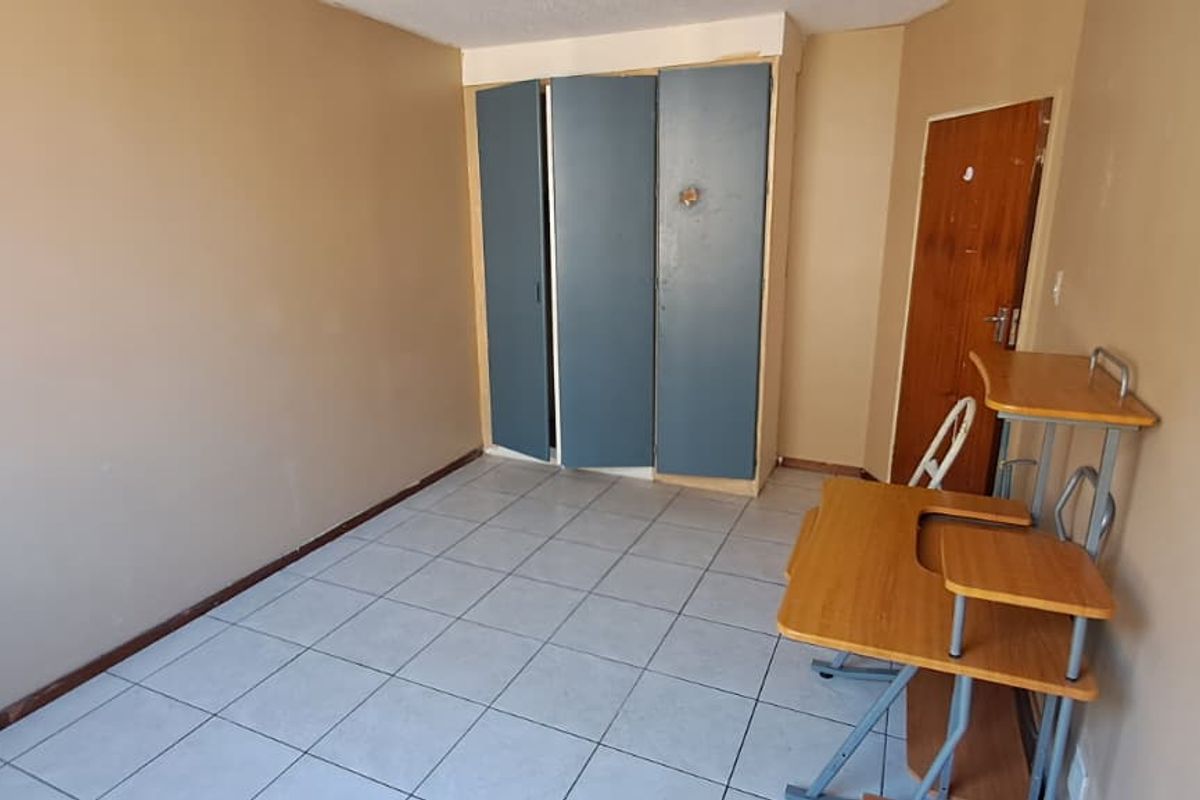 A bedroom featuring tiled flooring and built-in cupboards, requiring cosmetic updates to improve its overall appeal and condition.